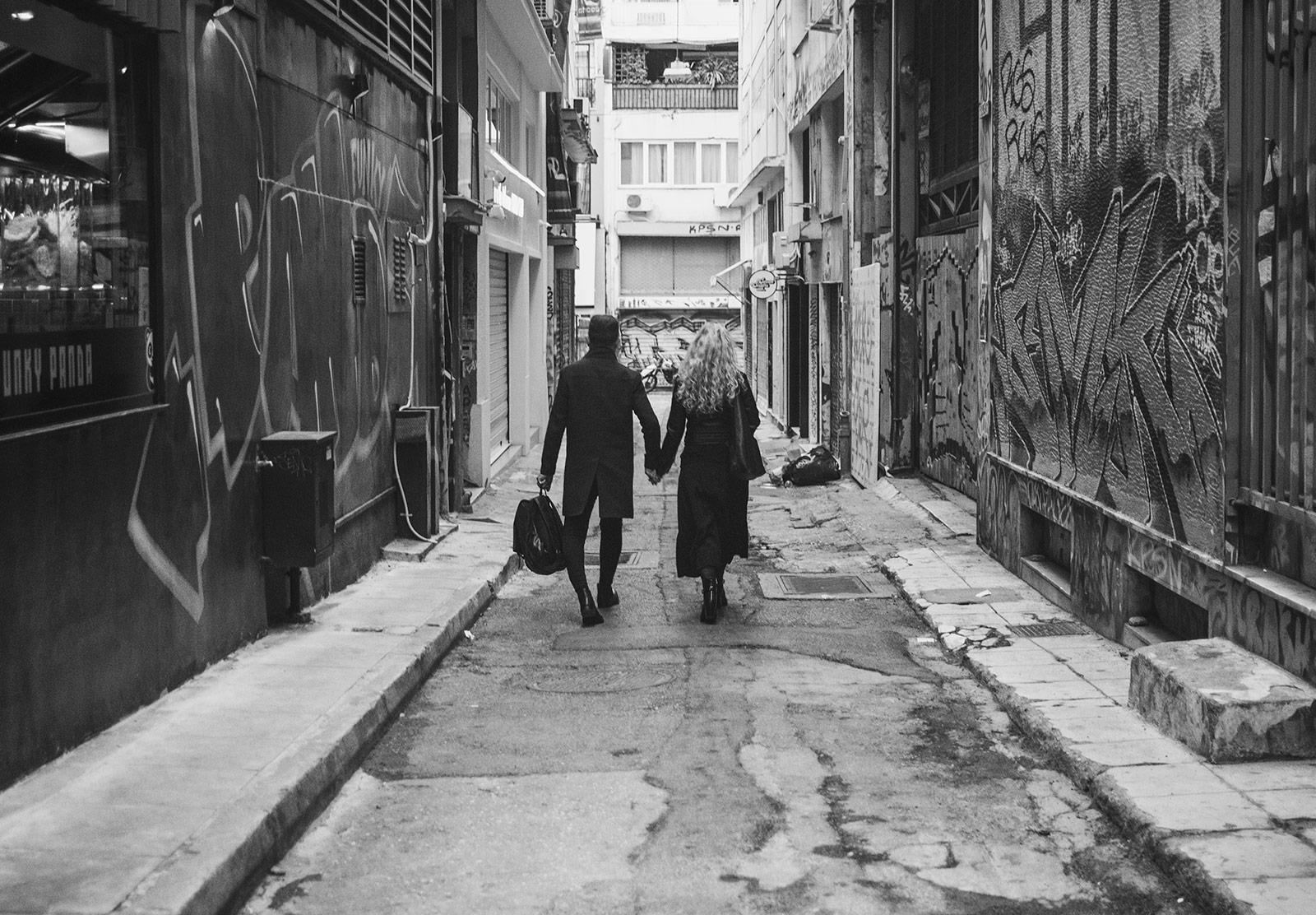 Couple holding hands in side street
