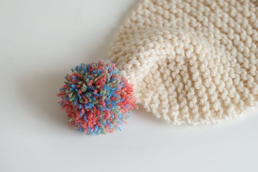 Multicoloured pompom on scarf