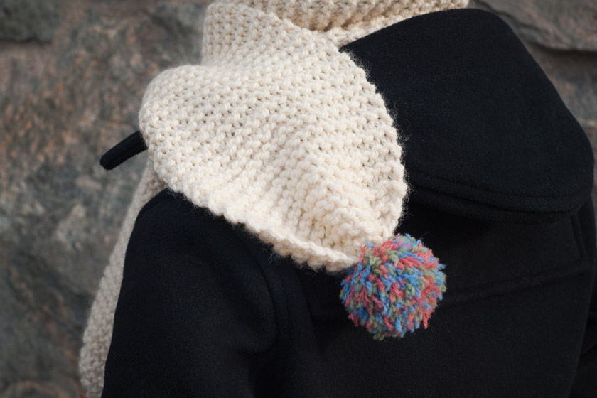 Knitted pompom scarf on shoulder