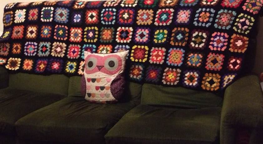 Multi-coloured granny square blanket on sofa