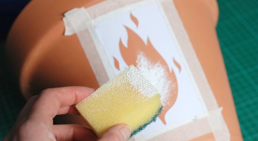 Applying white paint to a pot with a sponge