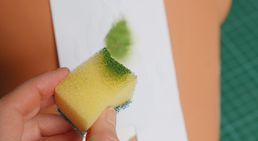 Sponging green paint onto pot
