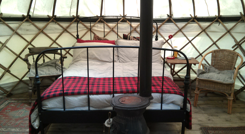 Double bed and wood burner in yurt