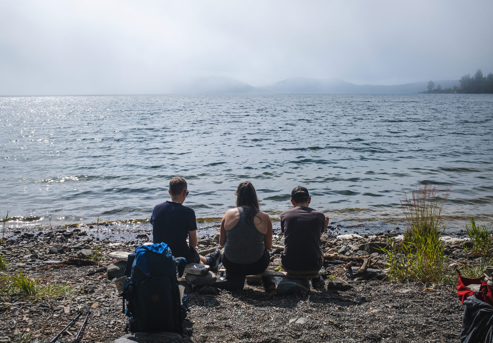 Three people sat on beach