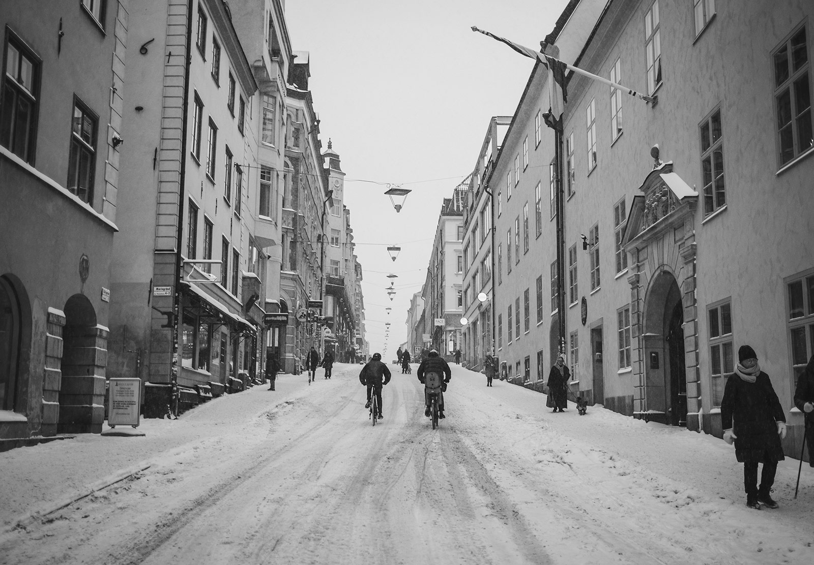 People cycling up snow covered street