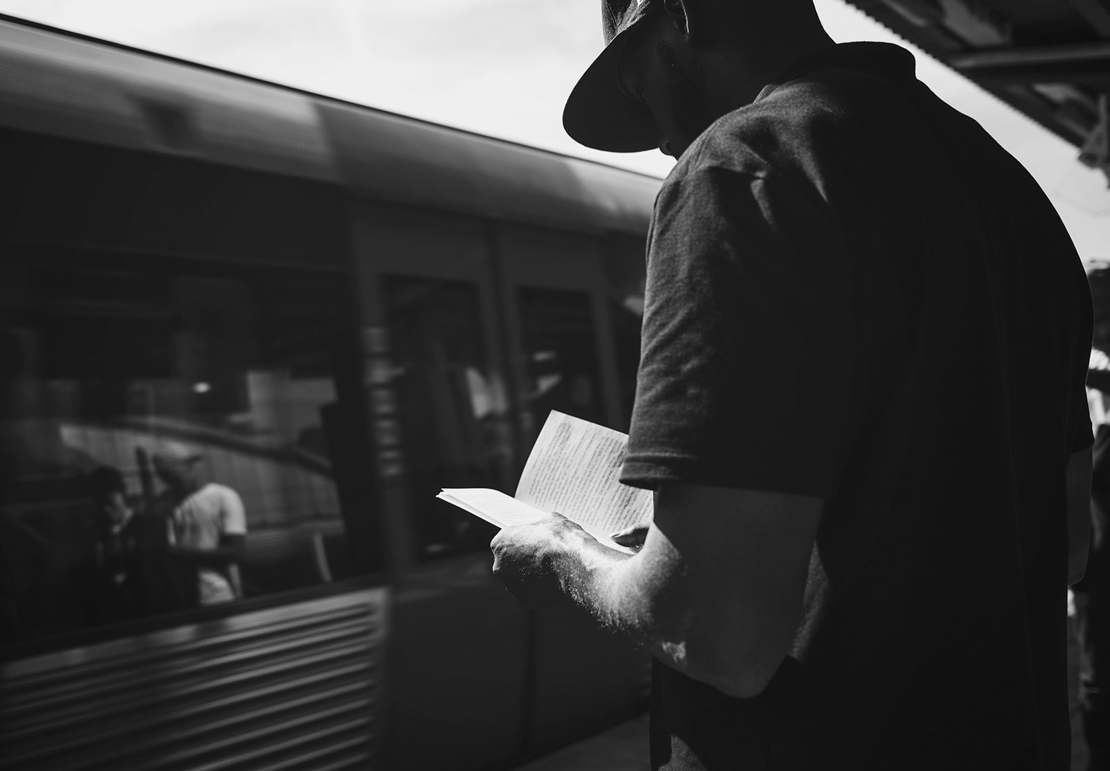 Man reading book on train platform