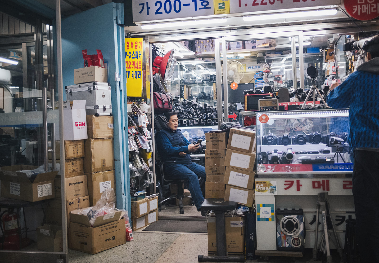Man sitting in cluttered camera shop
