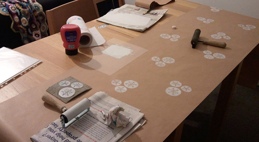 Brown paper being hand printed with white ink