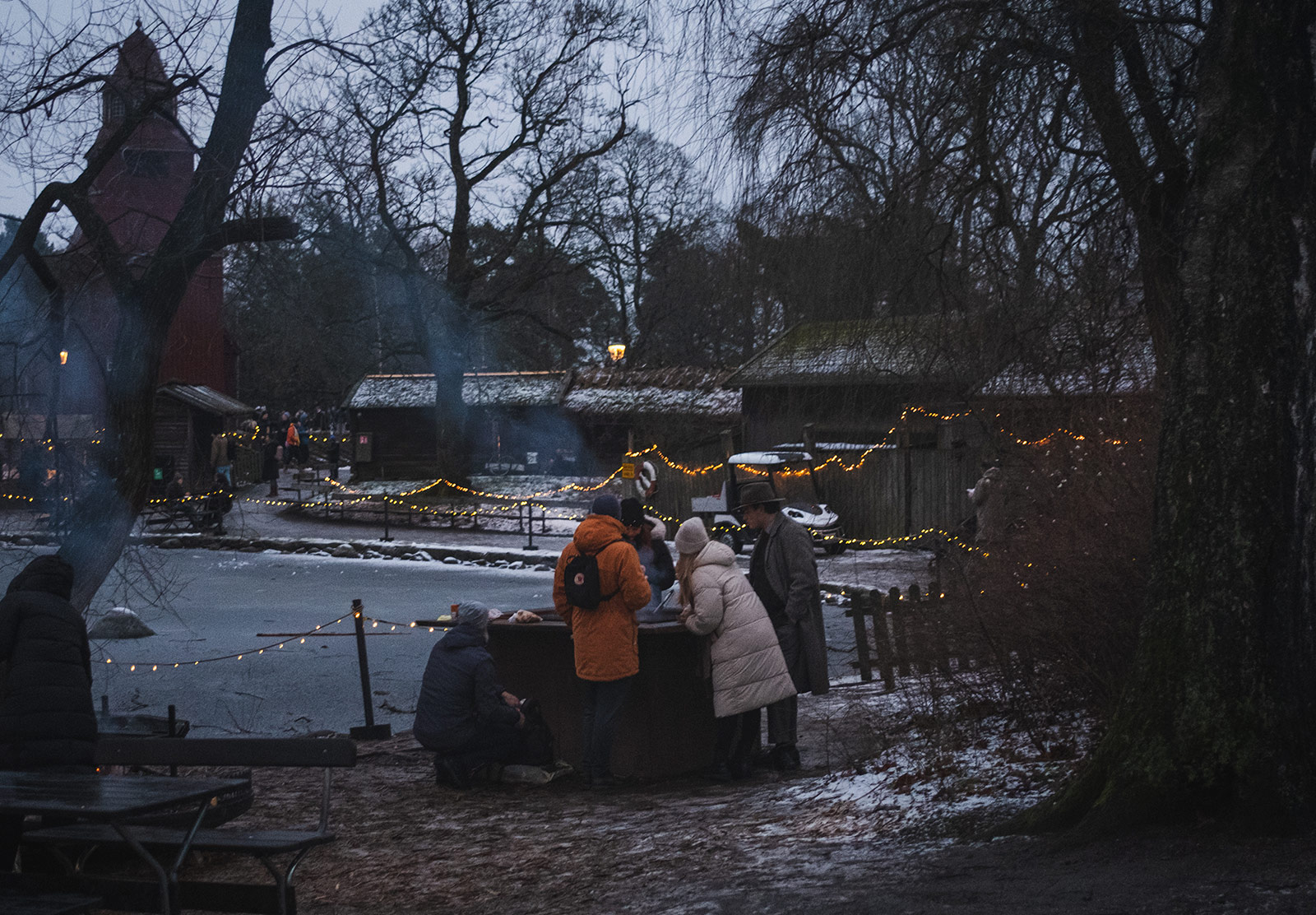 People cooking sausages on an outdoor grill, in the snow