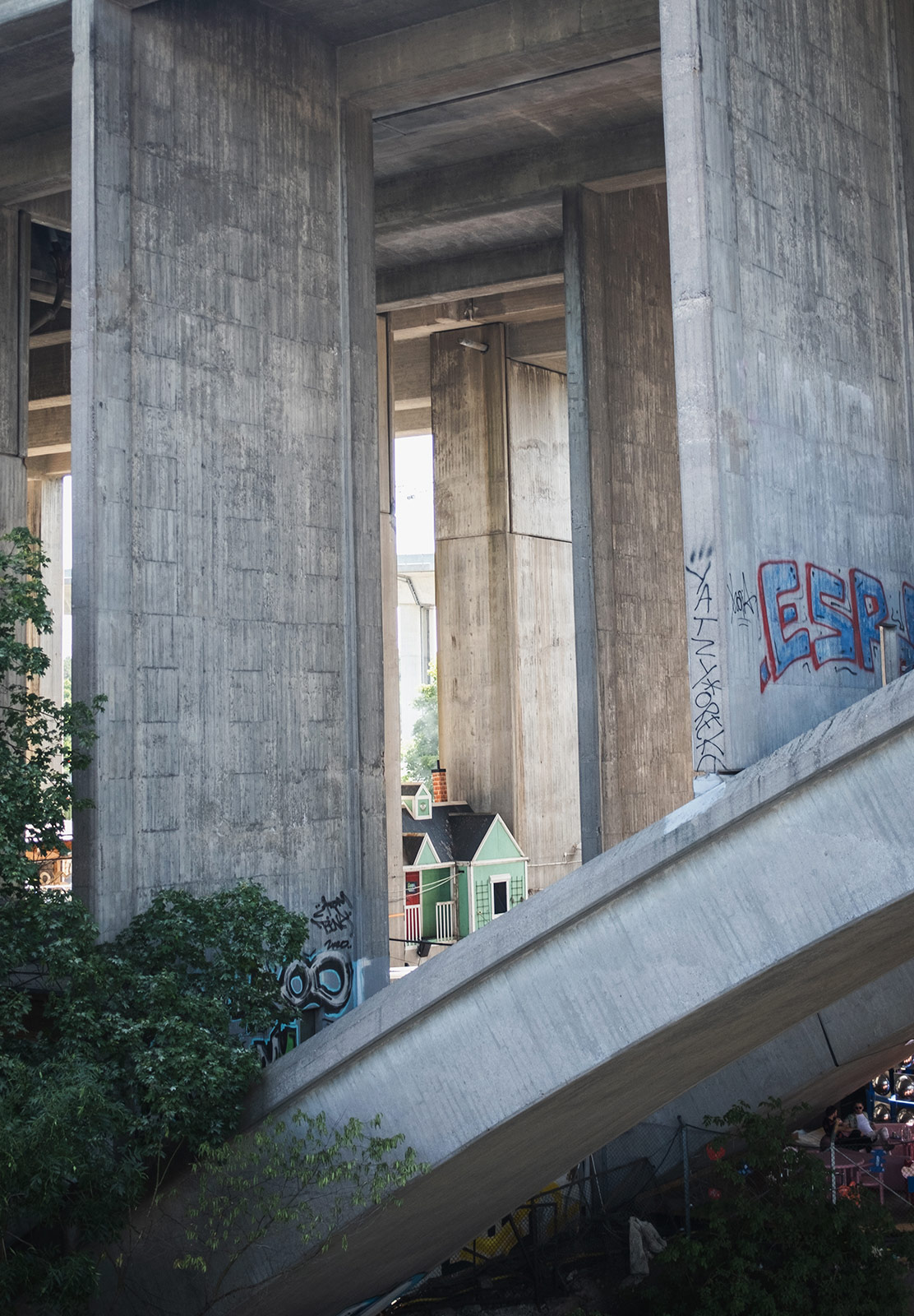 Tiny wooden house under large concrete bridge