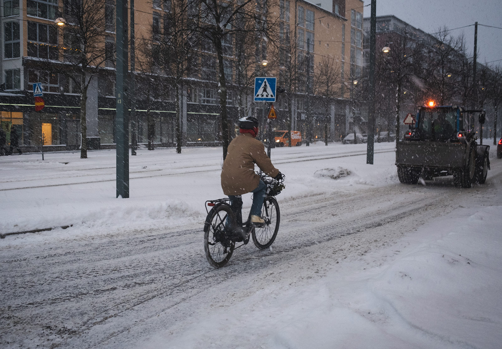 Person cycling behind snowplough