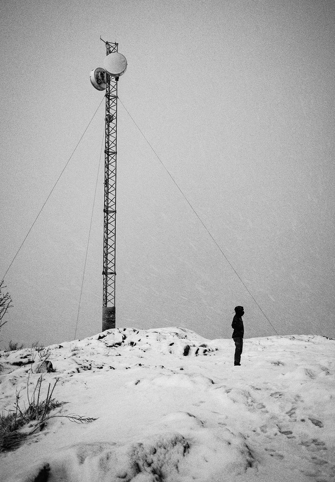 Man stood in snow next to mast