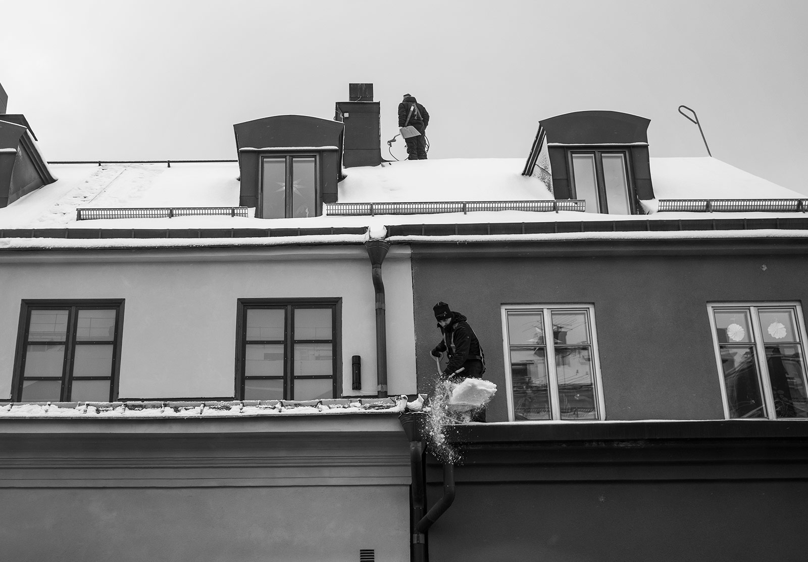 Men shovelling snow off roof
