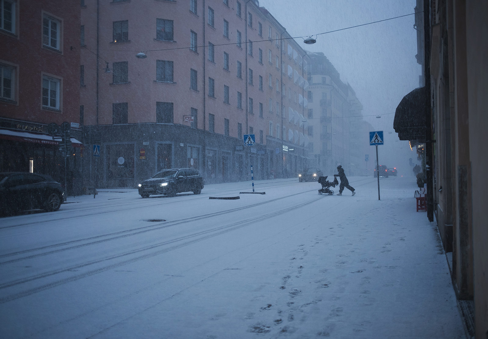 Person crossing the road with pram in a blizzard