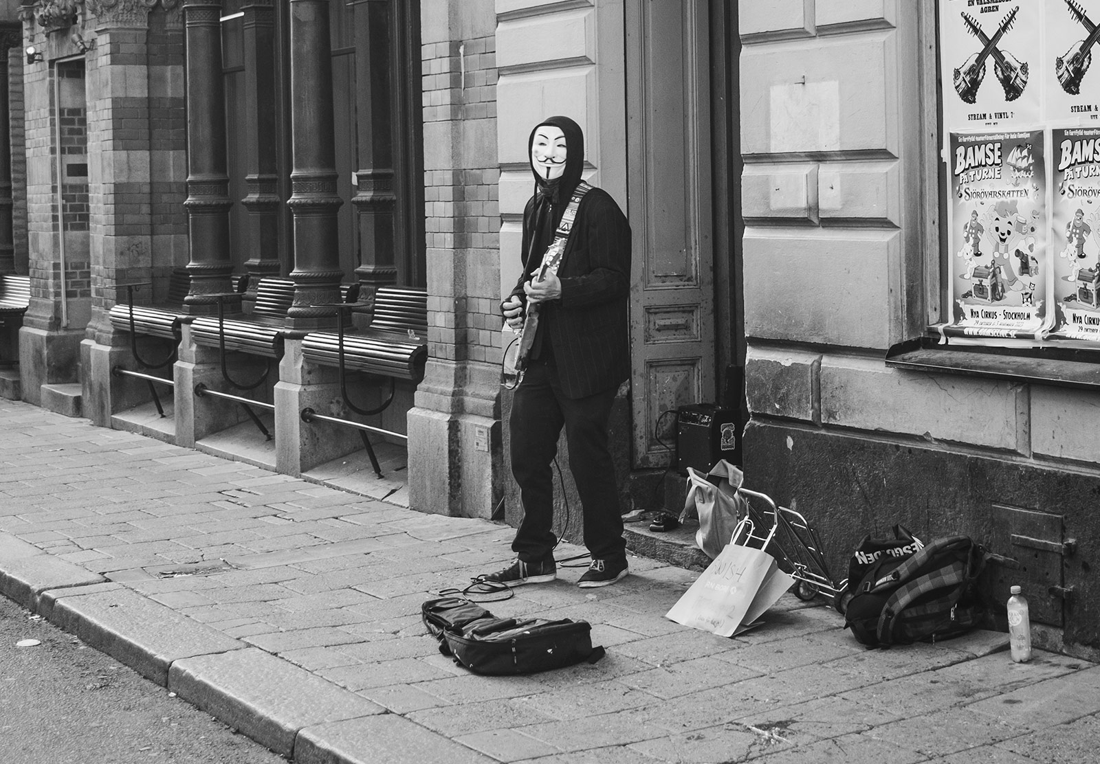 Man busking in an Anonymous mask