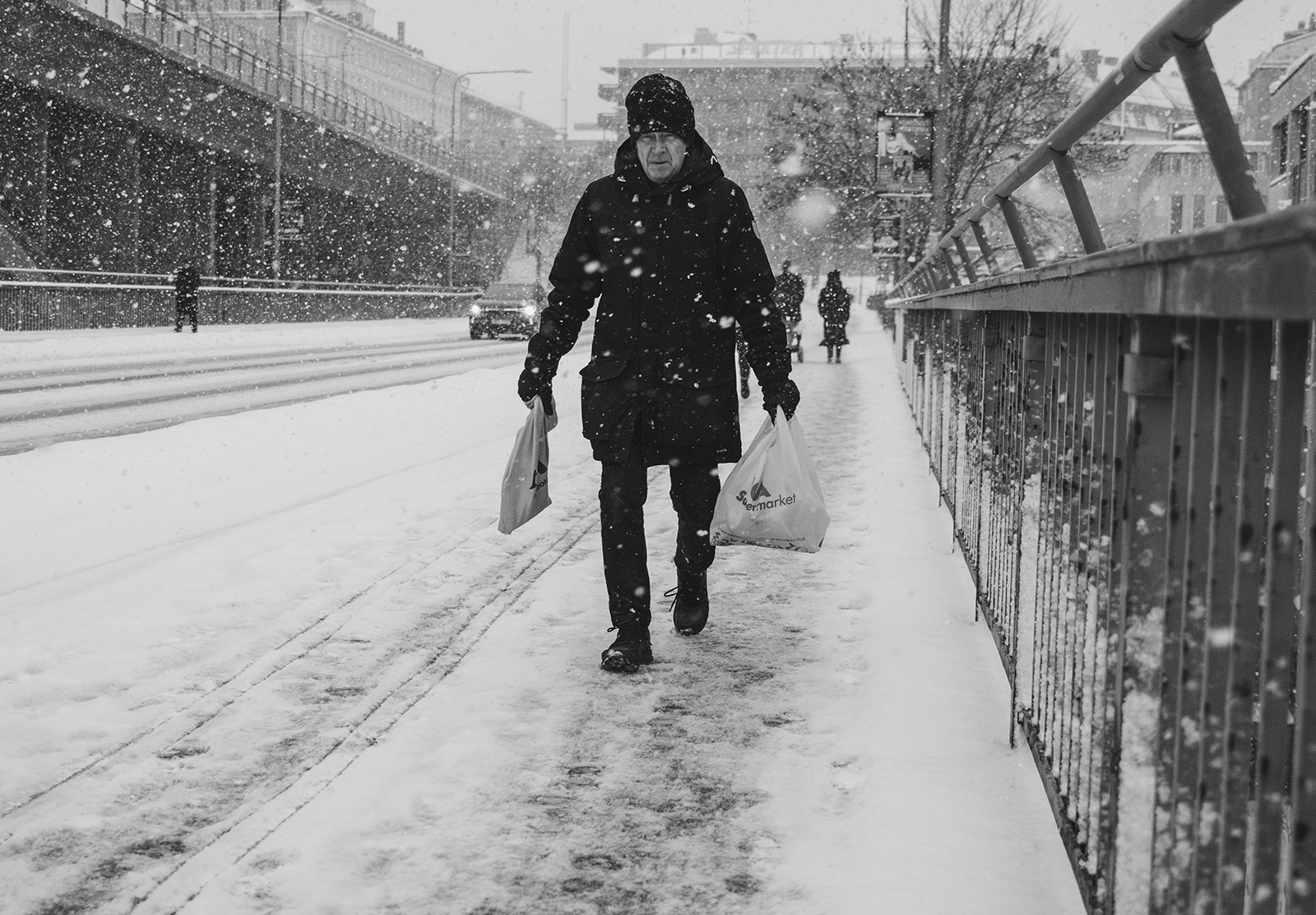 Man carrying shopping bags through snow