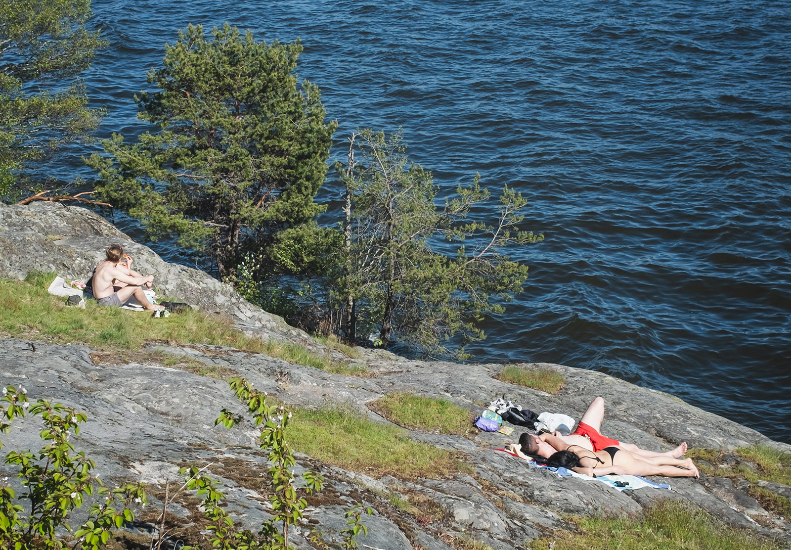 People sunbathing on rocks next to water