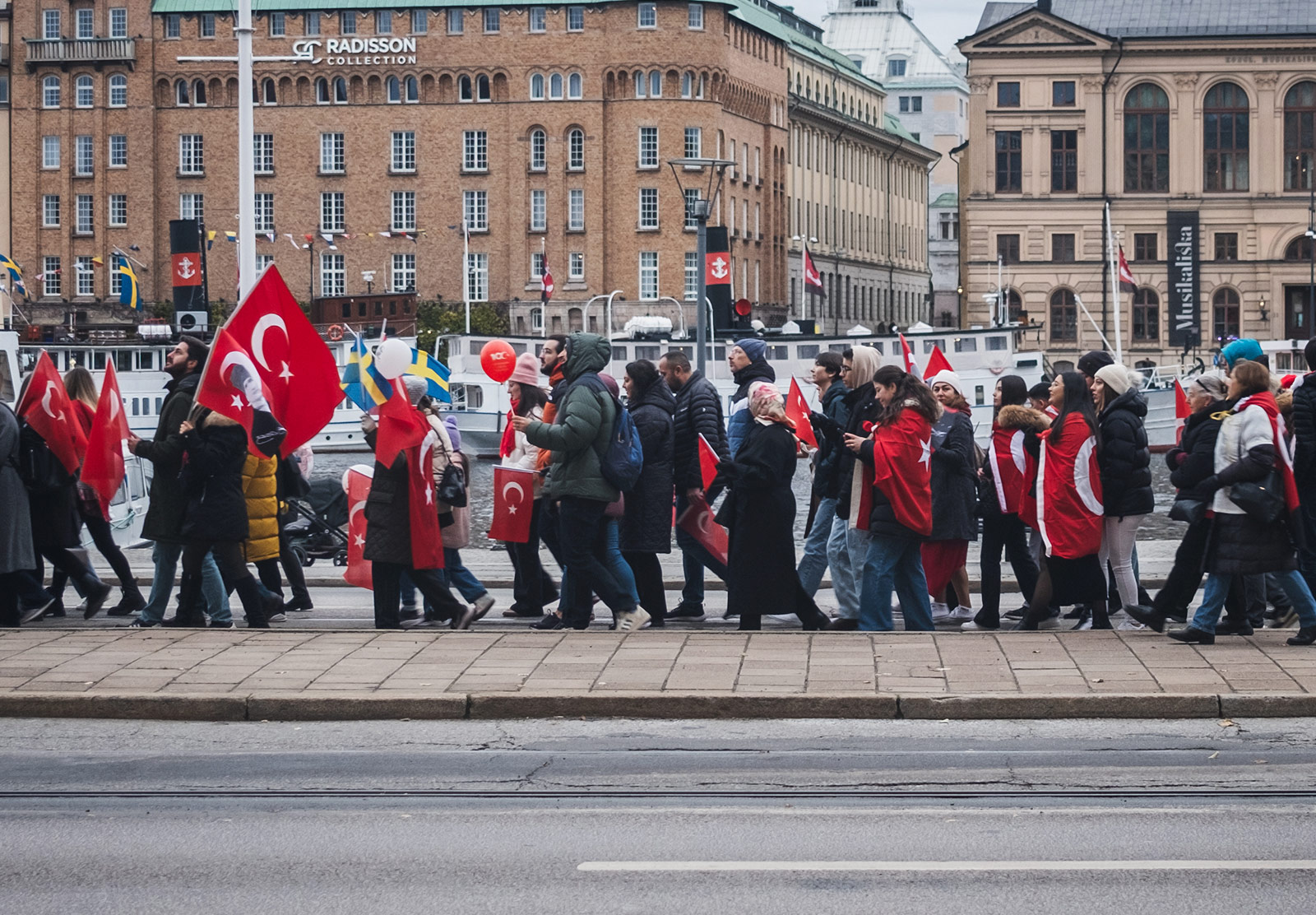 Group of people marching with Turkish and Swedish flags