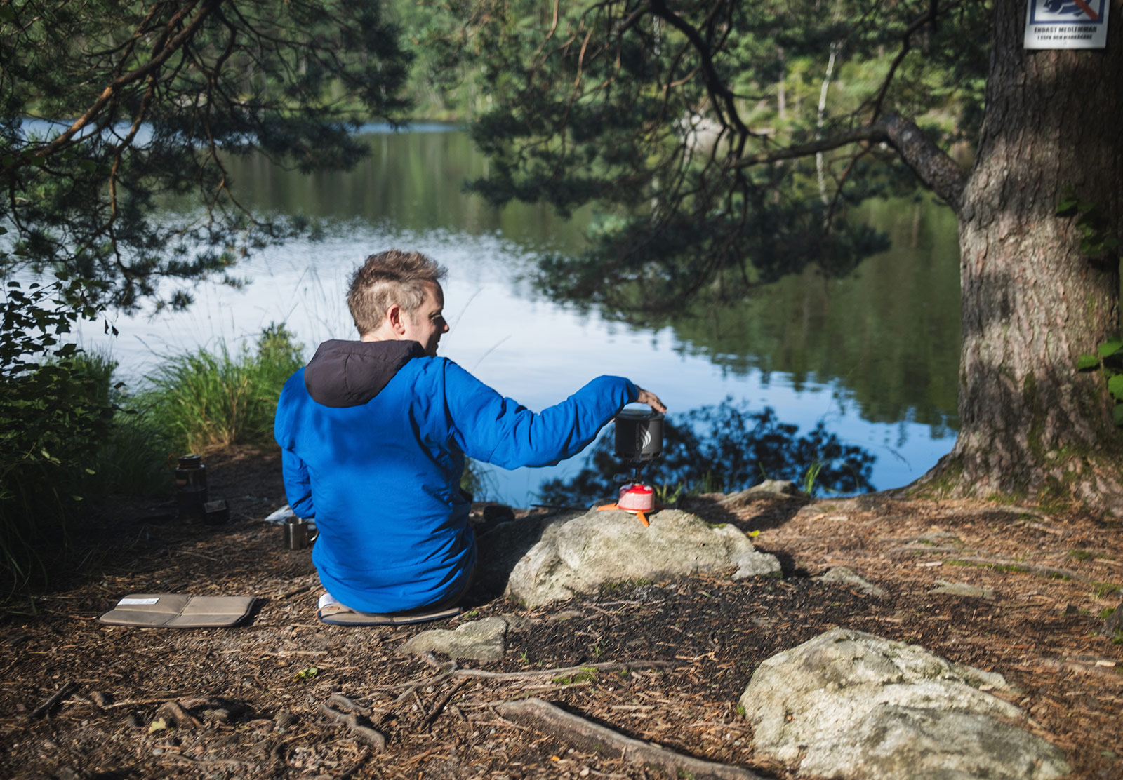 Man sitting by lake with stove