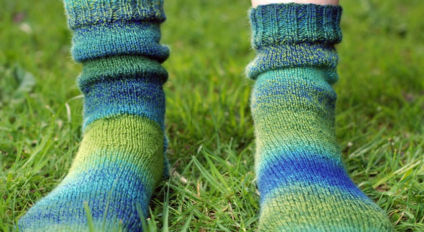 Green and blue knitted socks on grass