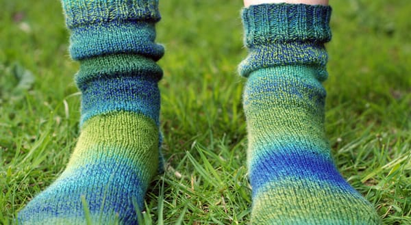 Green and blue knitted socks on grass